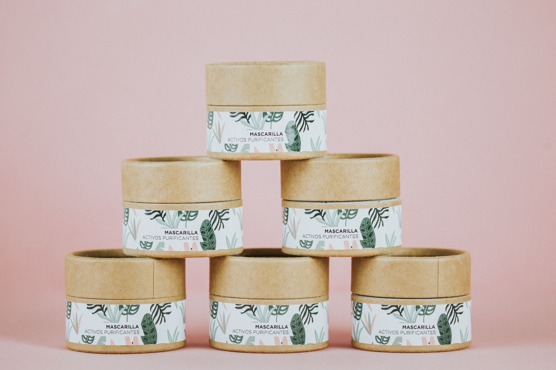 A stack of skincare jars on a pink backdrop